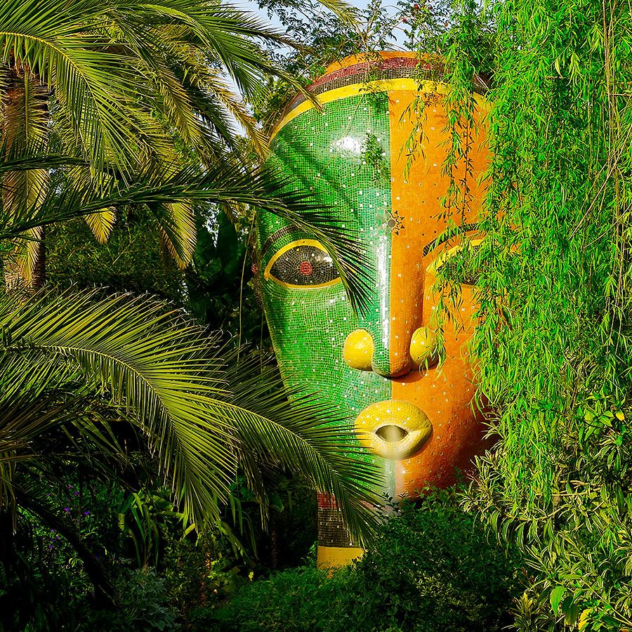 Riesiges Mosaikgesicht in Grün und Orange zwischen Palmen im Anima-Garten an der Ourika-Straße