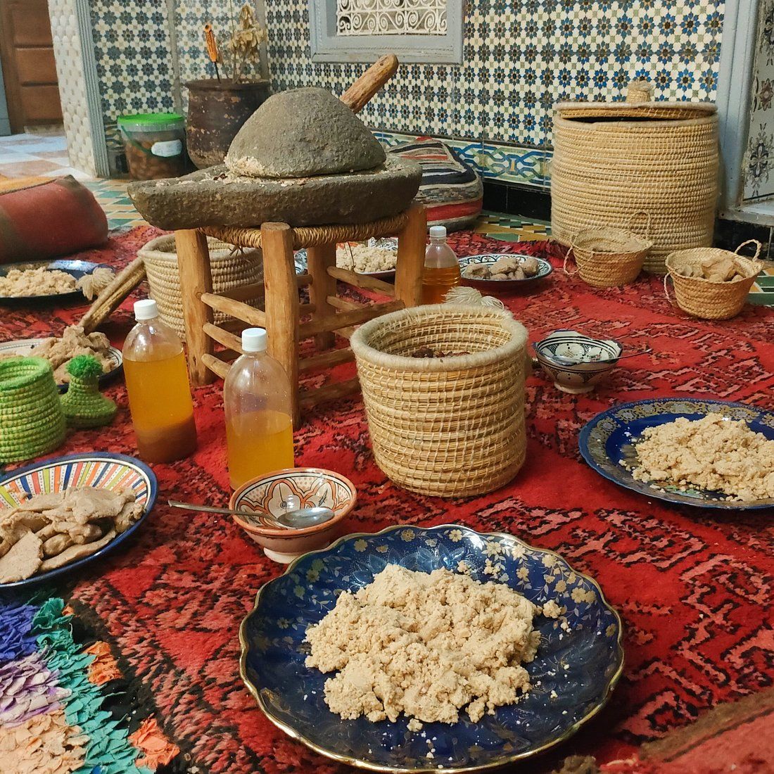 Meule en pierre, bouteilles d'huile d'argan et assiettes de pâte d'argan dans une coopérative