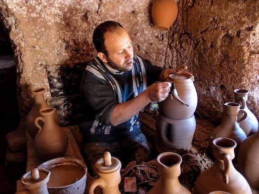 Potter finishing a jar among rows of clay pots