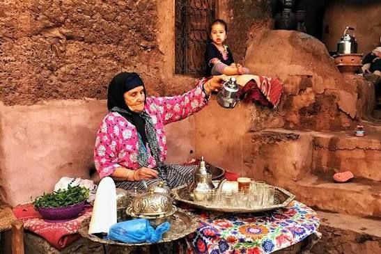 Woman preparing mint tea in the courtyard of an earth house